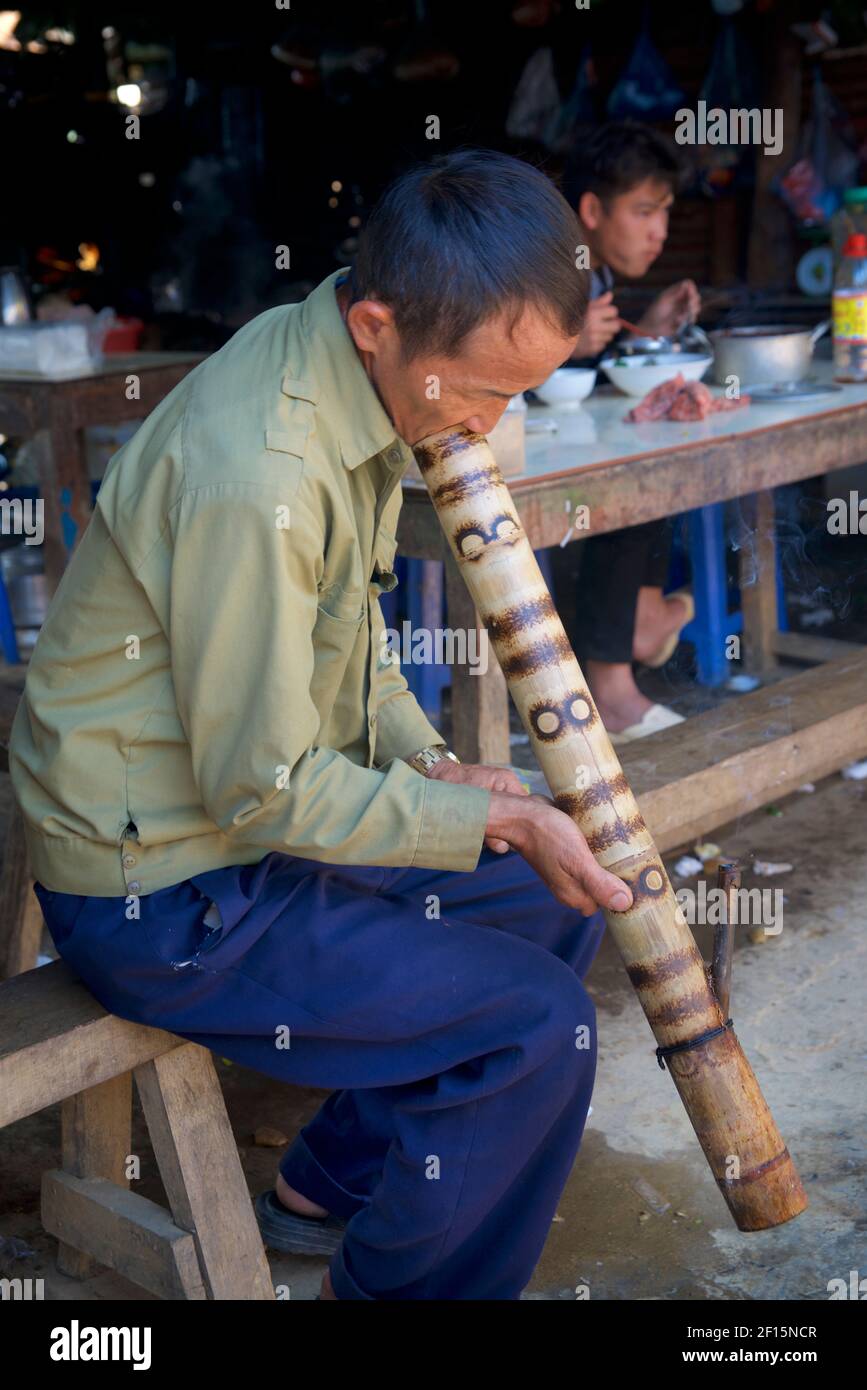 Vietnamese man at Can Cau market smoking from a bamboo water bong Stock ...