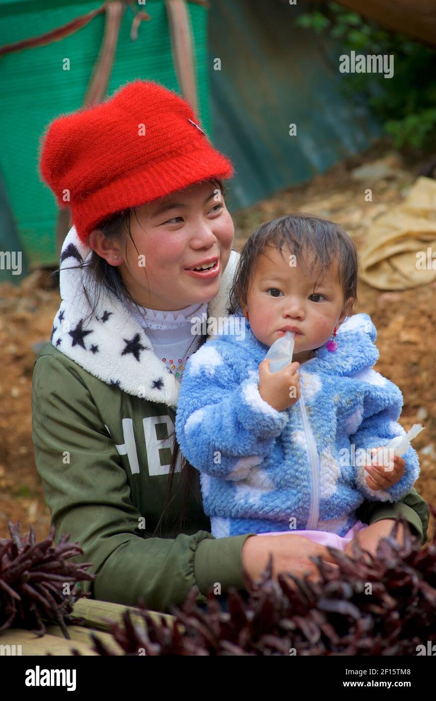 Young Vietnamese mother with her young child. Selling red dried chilli peppers at Can Cau market, Vietnam, Lao Cai province, Vietnam Stock Photo