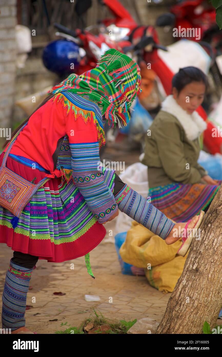 Flower Hmong woman in traditional style attire tightening her leg ...