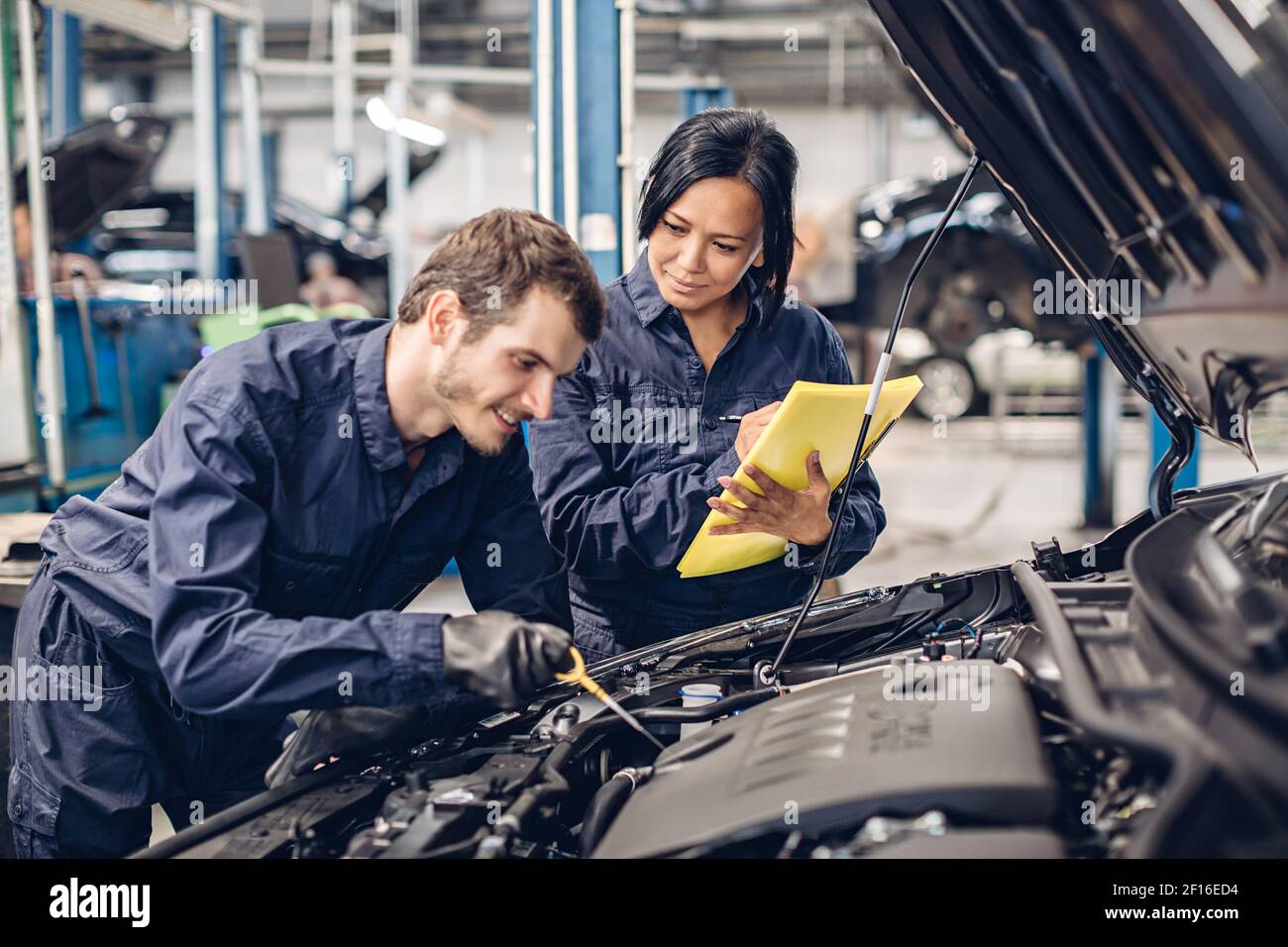 Auto car repair service center. Two mechanics - man and woman examining ...