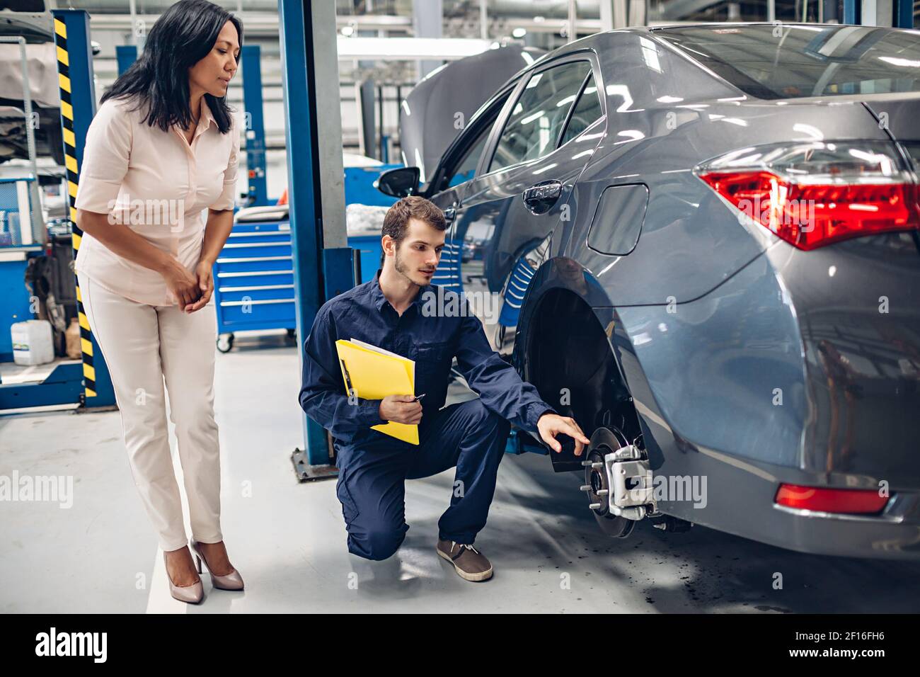 Auto car repair service center. A female customer and mechanic checking