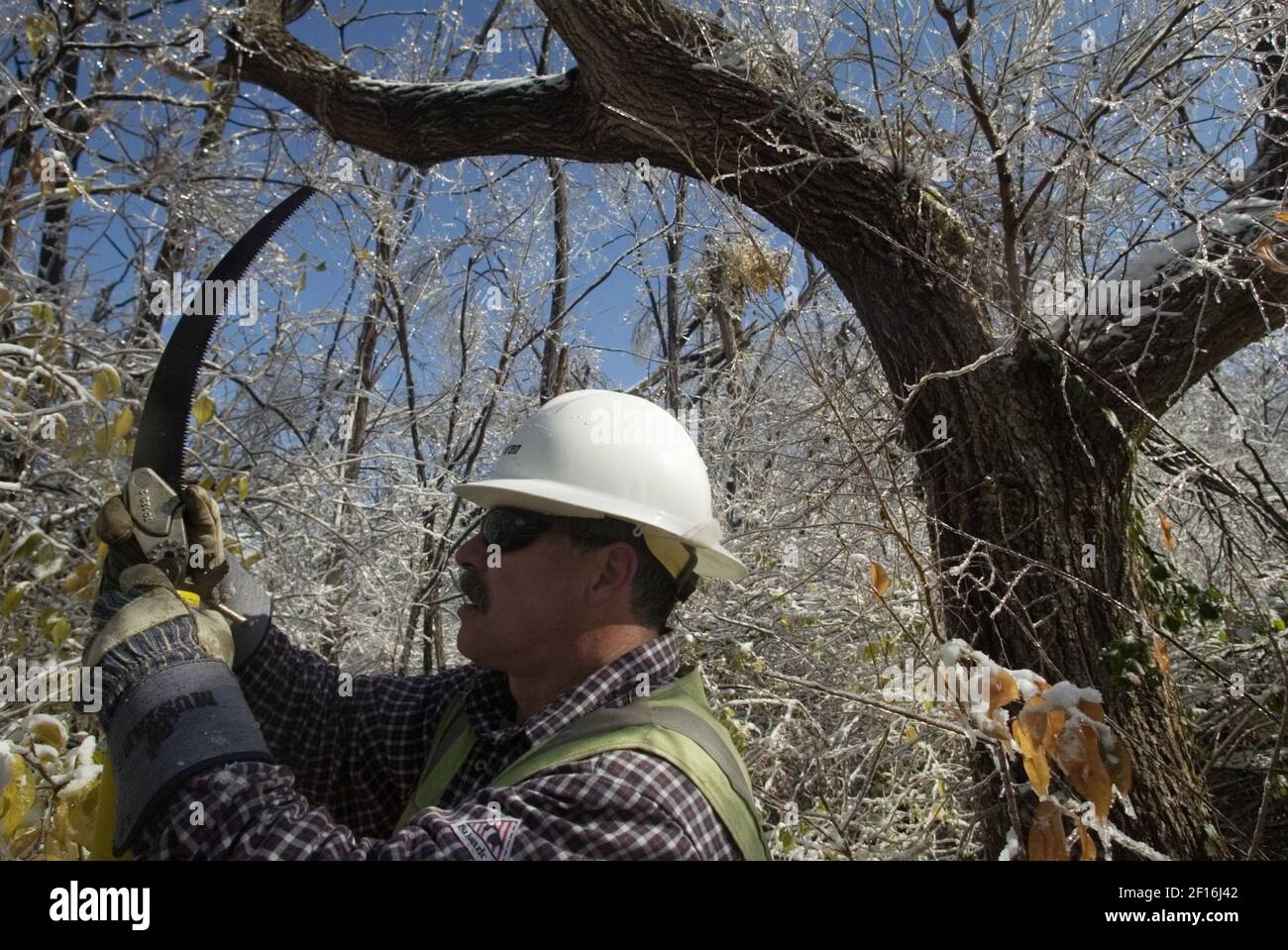 ameren-ue-apprentice-lineman-ken-moonier-mounts-a-saw-on-the-end-of-a-pole-to-clear-branches-in-danger-of-breaking-power-lines-on-saturday-december-2-2006-in-black-jack