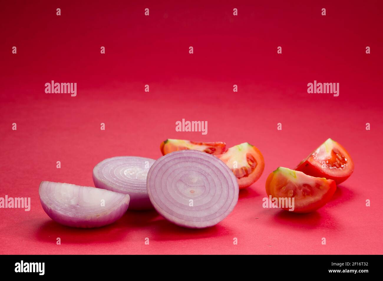 Tomato and onion slices arranged on a red textured background Stock ...
