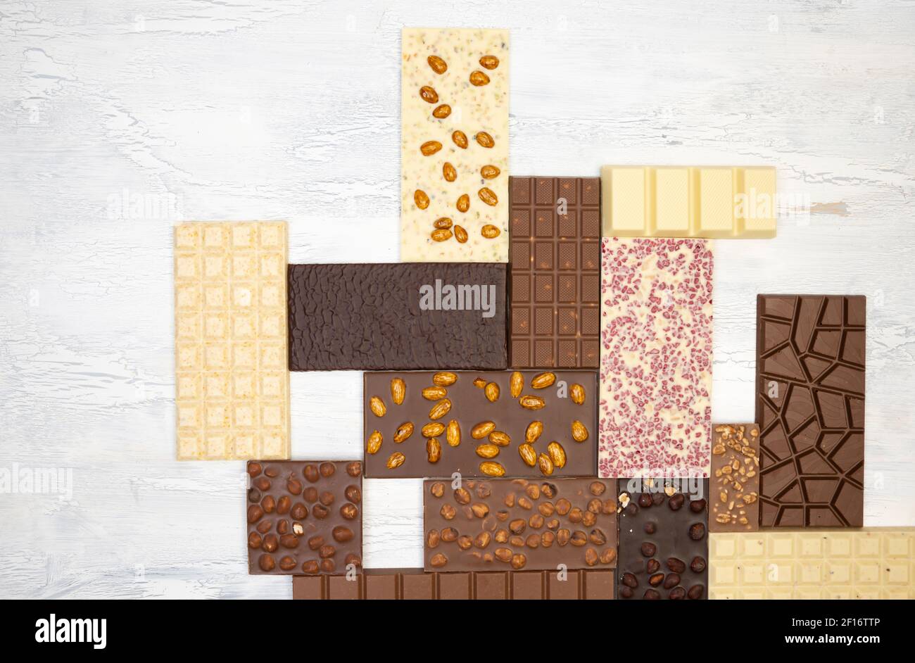 a lot of different sweet, delicate chocolate bars lie creatively on a white wooden background Stock Photo