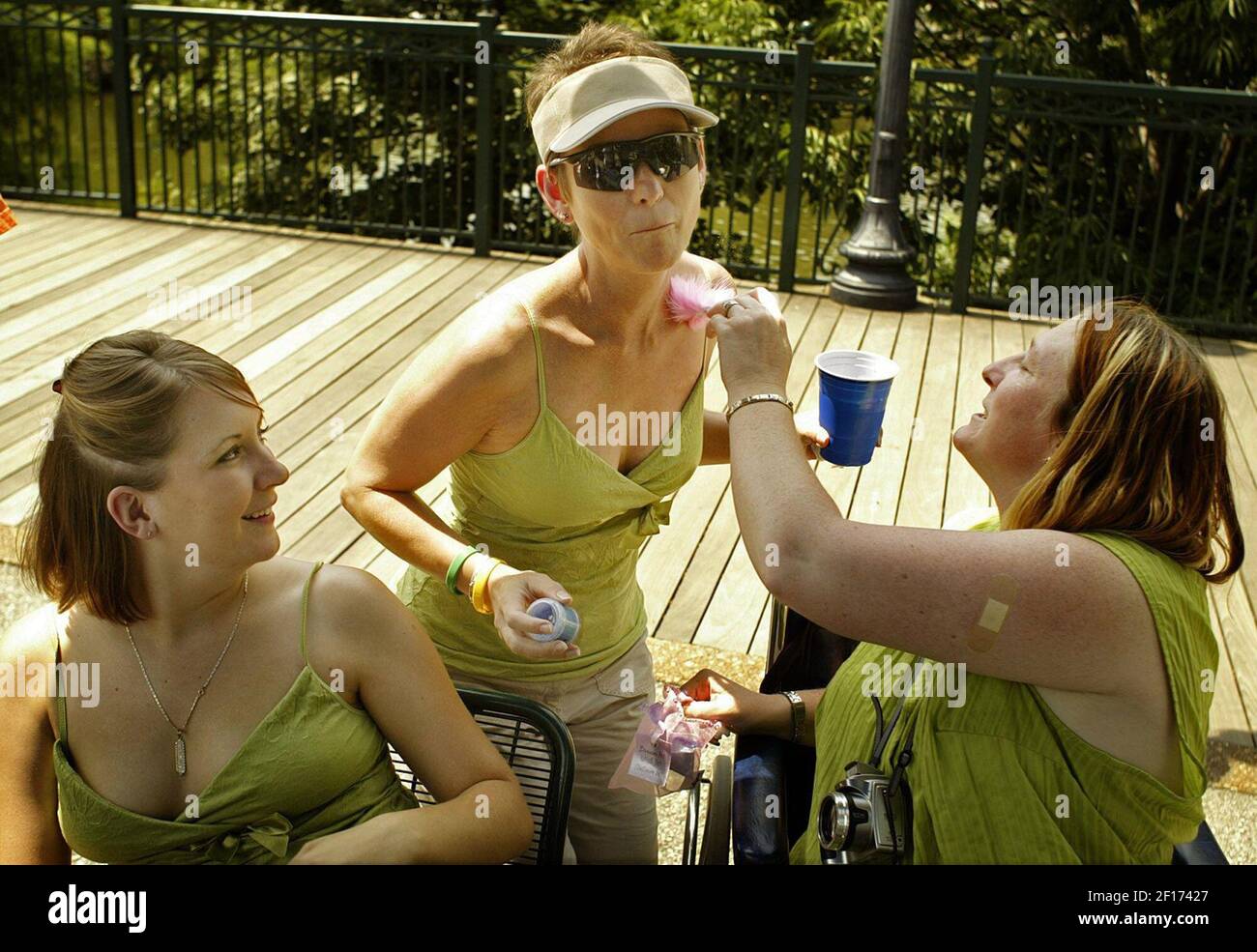 Katy Melo, right, puts glitter on Carolyn Evans, center, as Amber 