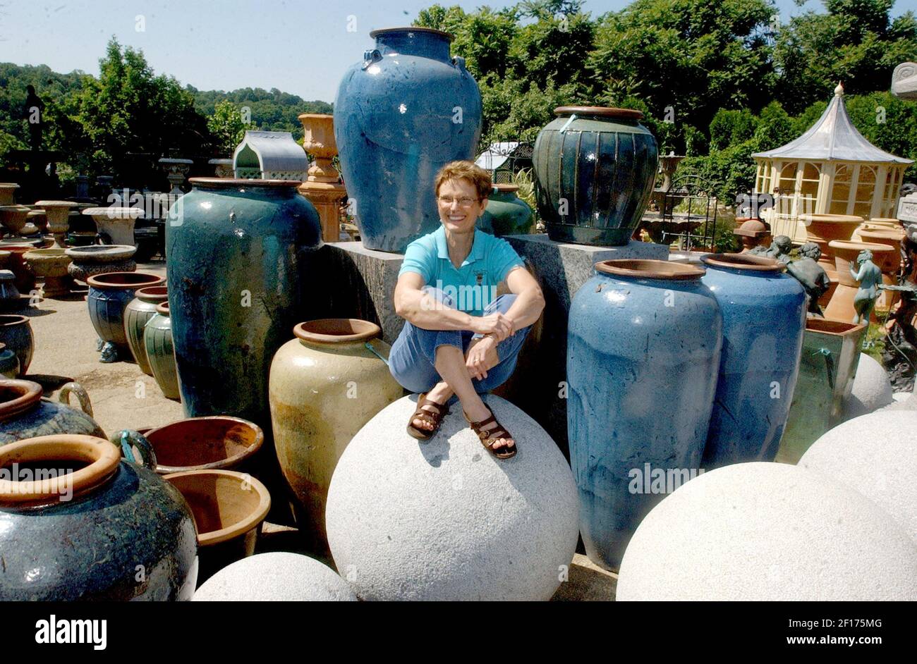 Elizabeth Schumacher sits among the giant pots for sale at her business