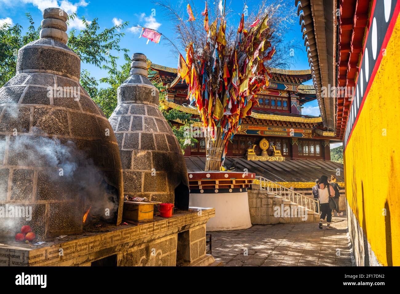 Guishan Dafo temple view with steaming offering burning and prayer flags Dharma wheel in background in Dukezong old town in Shangri-La Yunnan China Stock Photo