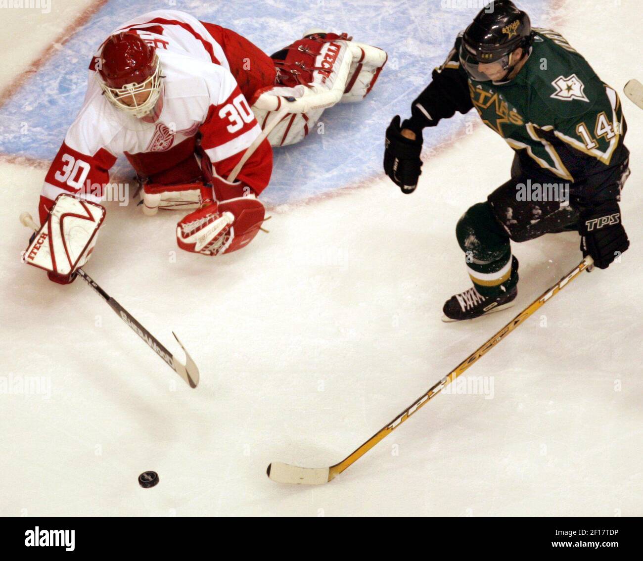 Detroit Red Wings goalie Chris Osgood, left, stops a Los Angeles Kings  Justin Williams (14) shot as Red Wings defenseman Brad Stuart (23) looks on  in the second period of an NHL