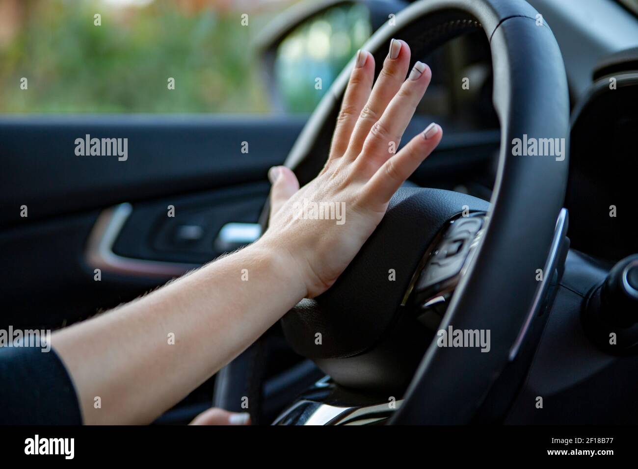 female hand presses the horn on the steering wheel of a modern car. no face Stock Photo