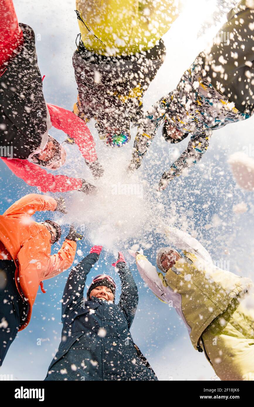Group of happy friends at ski resort are having fun and throwing snow Stock Photo
