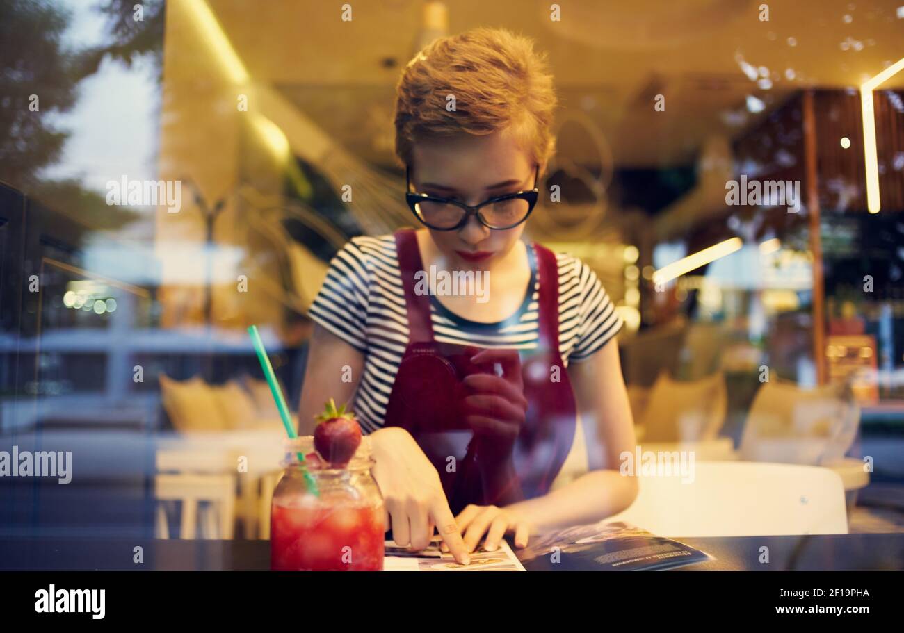 fashionable woman in red sundress sits in a cafe and mirror glass