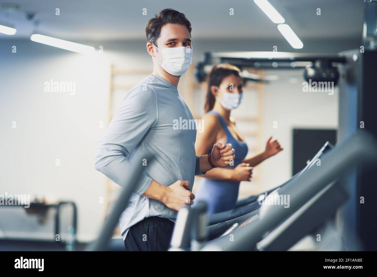 Two people working out on treadmill in masks Stock Photo