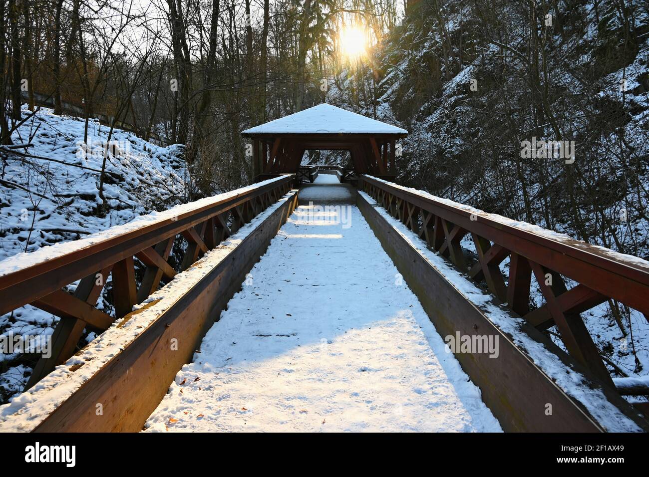 Beautiful snowy wooden bridge with a path for hiking. Winter season ...