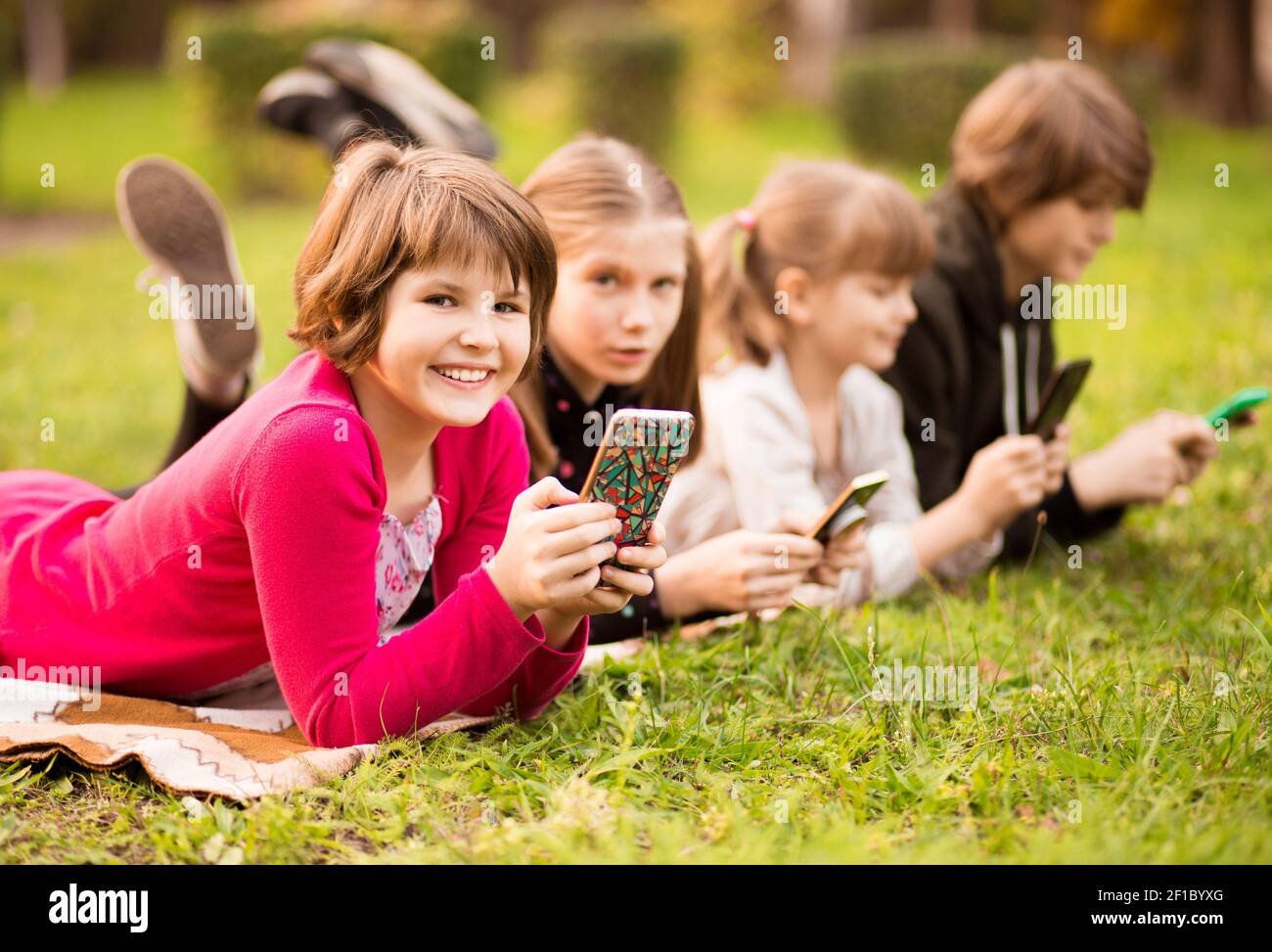 Outdoor portrait of little girls and boys playing with phones . High quality photo Stock Photo