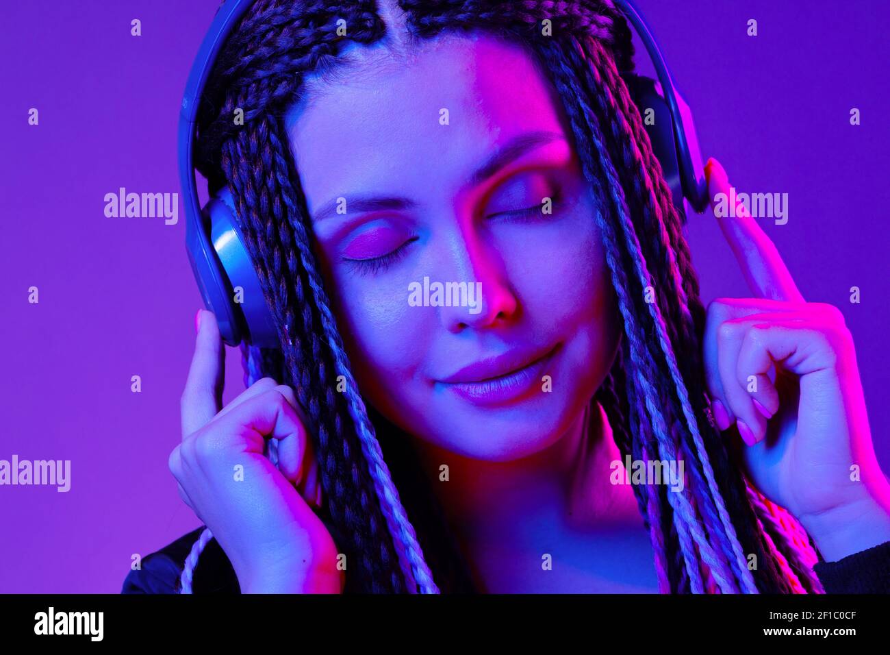 Beautiful woman with long hair in braids listening to music with ...