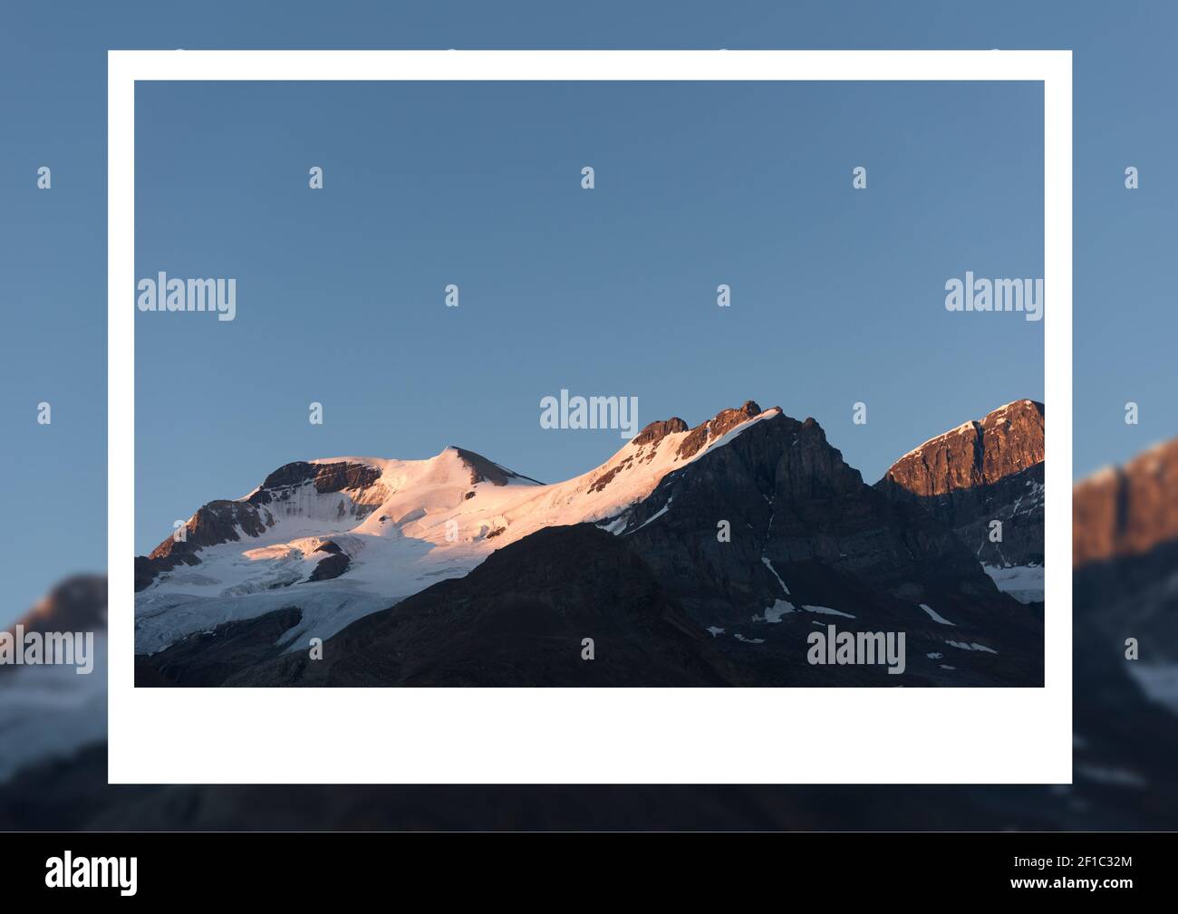 Composition of instant image white border frame over colour image of blue sky and mountain peaks Stock Photo