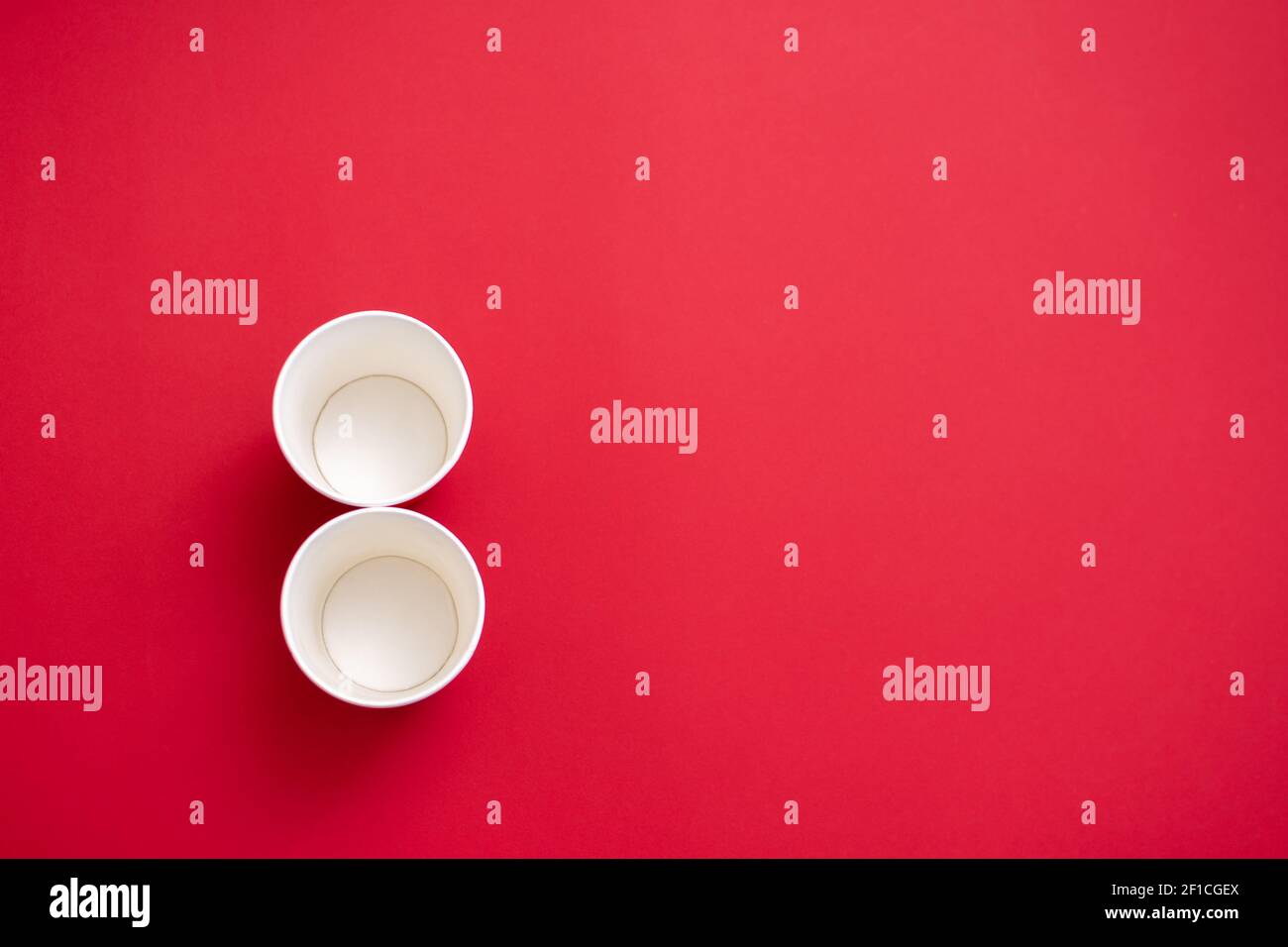 Two empty paper cups in the shape of the number 8. On a red background. Copy space for text Stock Photo