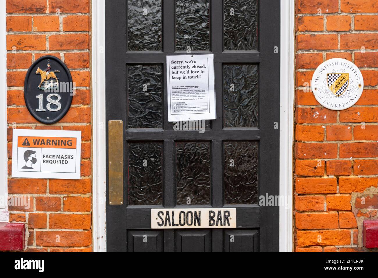 COVID 19 signs on entrance door to pub in Orsett, Essex, UK. The Foxhound Pub, closed during pandemic lockdown Stock Photo
