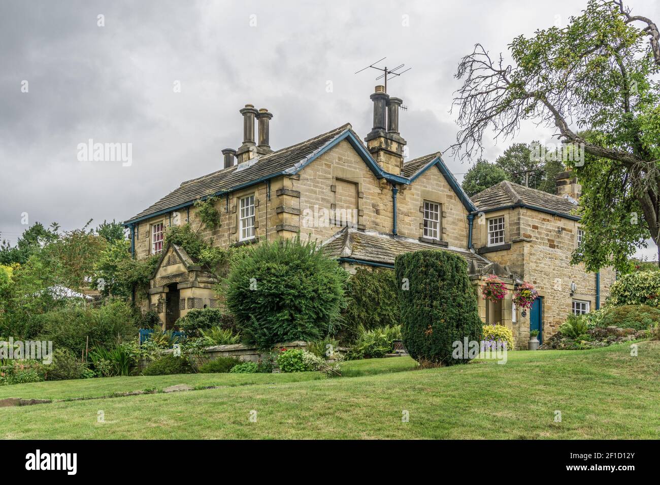Stormy skies over a detached stone built period property in the estate village of Edensor, Derbyshire, UK Stock Photo