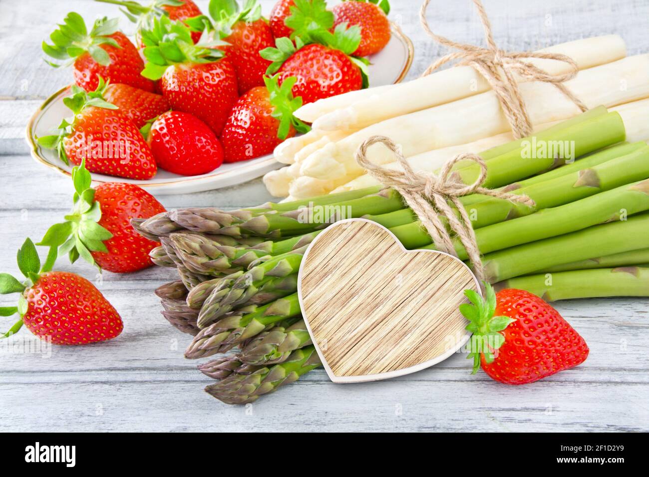 Fresh asparagus and strawberries with wooden heart Stock Photo
