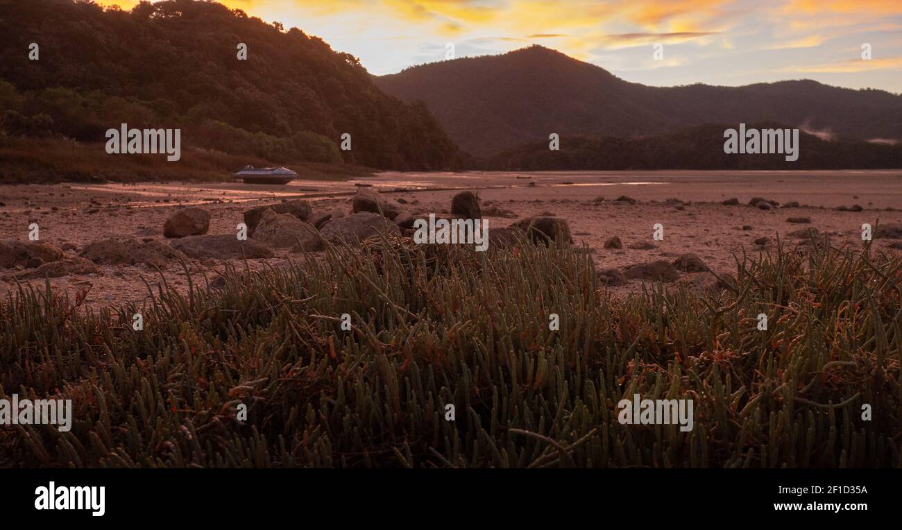 Red sunset landscape scenery in tropical inlet/bay with deserted boat ...