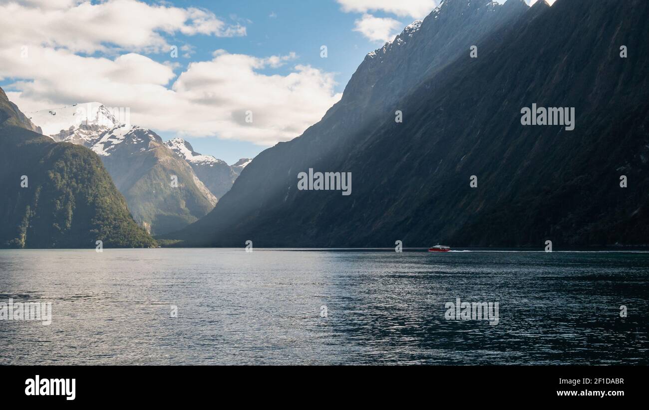 Boat sailing through fjord on a sunny day. Photo taken in Milford Sound, Fiordland National Park, New Zealand Stock Photo