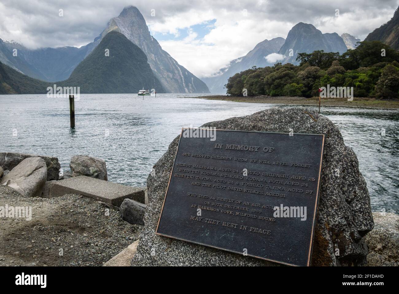 View on fjord with impressive mountains in backdrop and monument in foreground. Photo taken in Milford Sound, Fiordland National Park, New Zealand Stock Photo