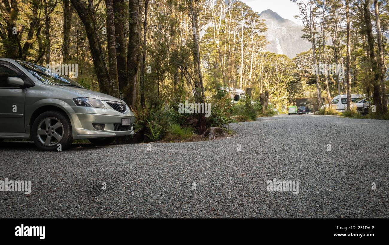 Sunset shot of campsite located in woods with camper vans, RVs and gravel path leading through frame,Photo taken in Milford Sound, Fiordland NP Stock Photo