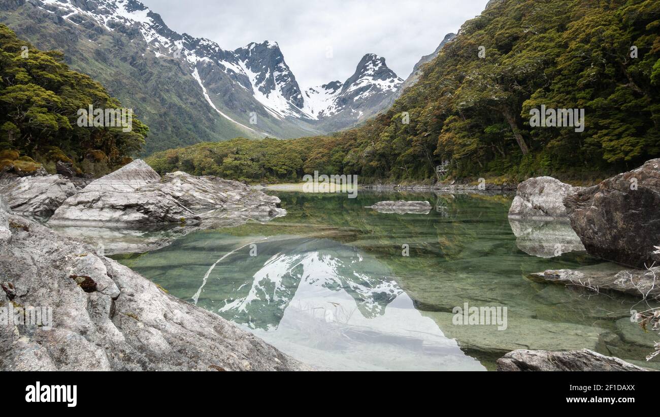 Pristine alpine lake reflecting surrounding environment. Shot on Routeburn Track, New Zealand Stock Photo
