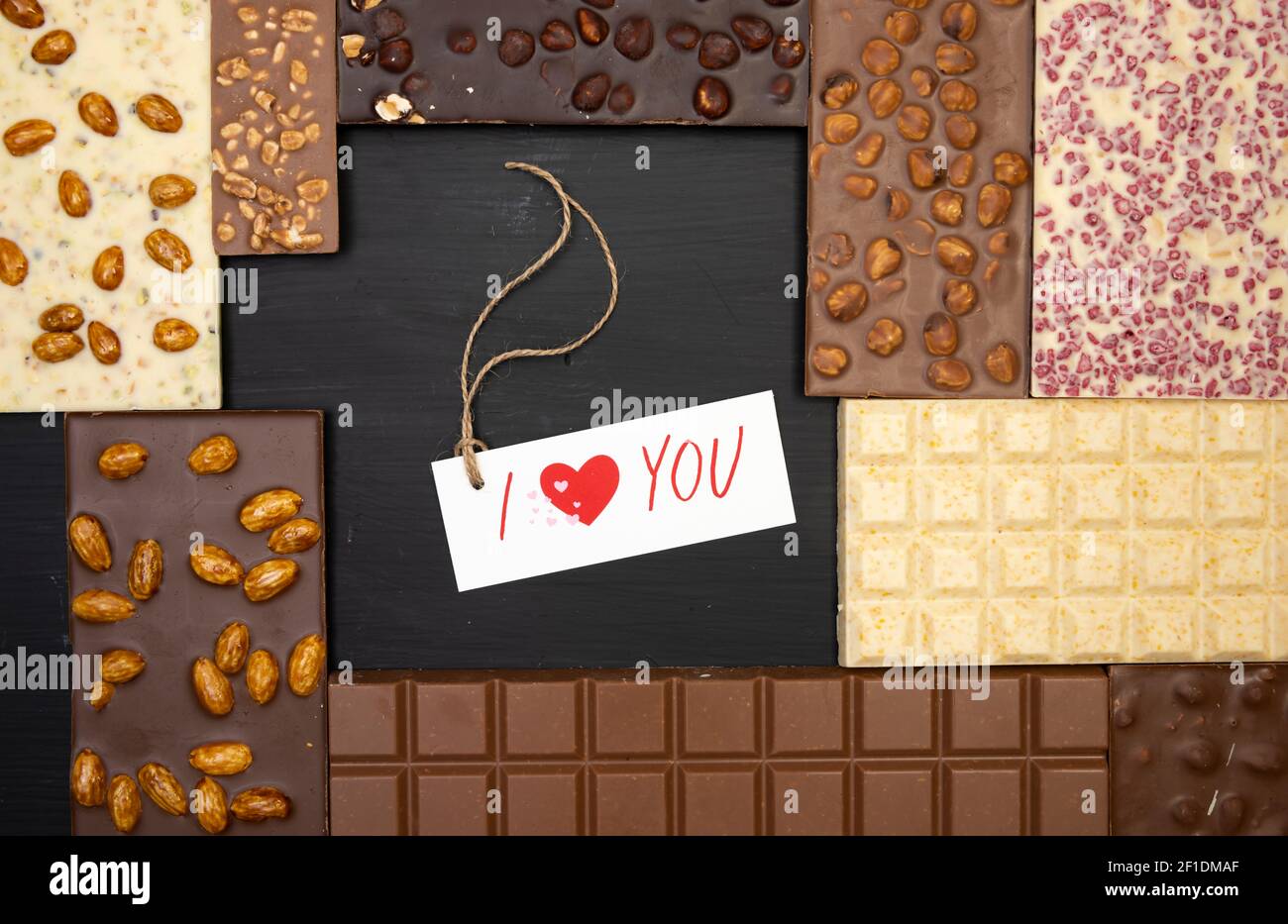 different sweet bars of chocolate lie on a black wooden background with a label that says I love you Stock Photo