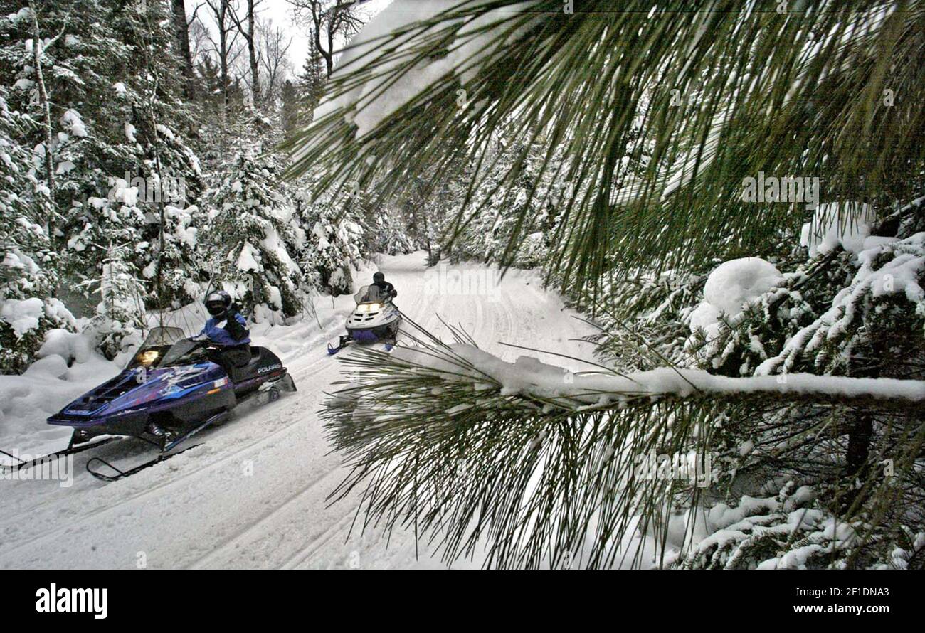 Snowmobilers glide down a trail in Jan. 2005 in Ely, Minn. Miserable winter weather for some means great business for others, such as snowmobile dealers, hardware stores and ski shops. (Photo by Marlin Levinson/Minneapolis Star Tribune/TNS/Sipa USA) Stock Photo