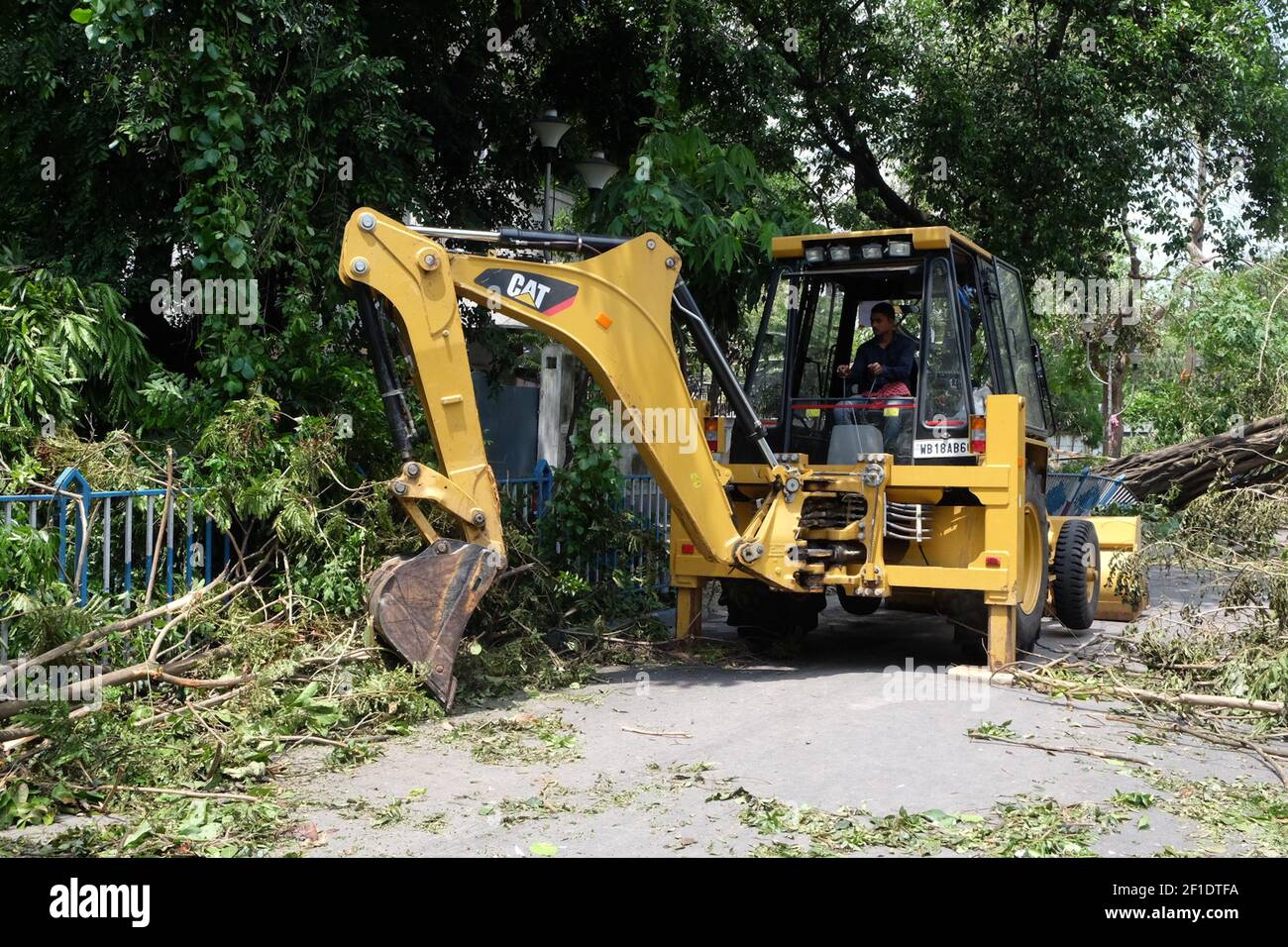 KMC workers have used a bulldozer to clear the uprooted trees over the road in Kolkata, the state capital, authorities struggled to remove debris from roads and clear trees that fell as the cyclone, packing winds of 133 km (83 miles) per hour, pounded the city of 14 million for hours. (Photo by Satyajit Shaw/Pacific Press/Sipa USA) Stock Photo