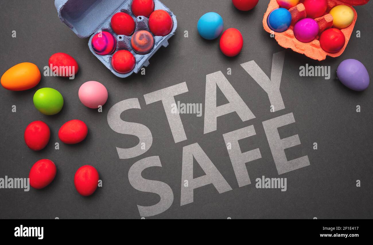 Easter holiday celebration at Covid19 pandemic Stay safe text message and Easter eggs on grey black color background, top view. Coronavirus days Stock Photo