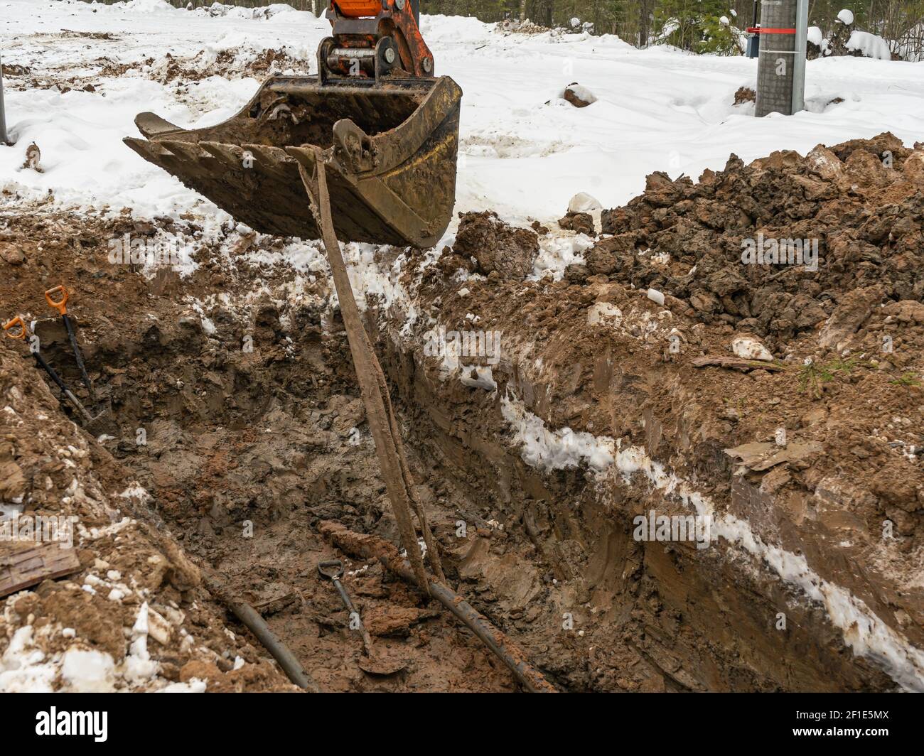 The excavator bucket digs a pit trench for laying engineering ...
