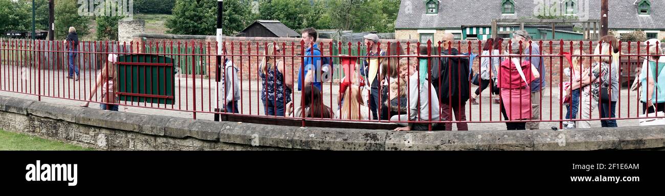 boy smiling through railings in disinterested crowd Stock Photo