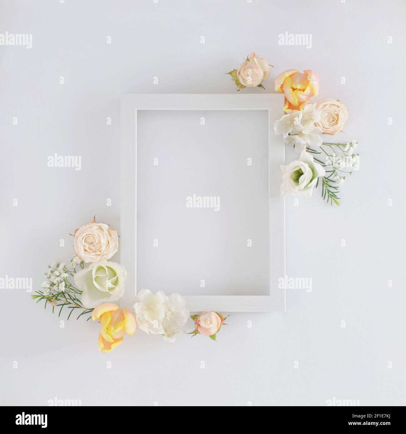 Creative layout made with colorful spring flowers and white frame over white background. Minimal flat lay holiday concept. Stock Photo