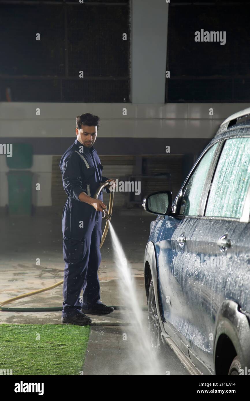 Technician  cleaning the car with a high pressure washer at a car wash Stock Photo