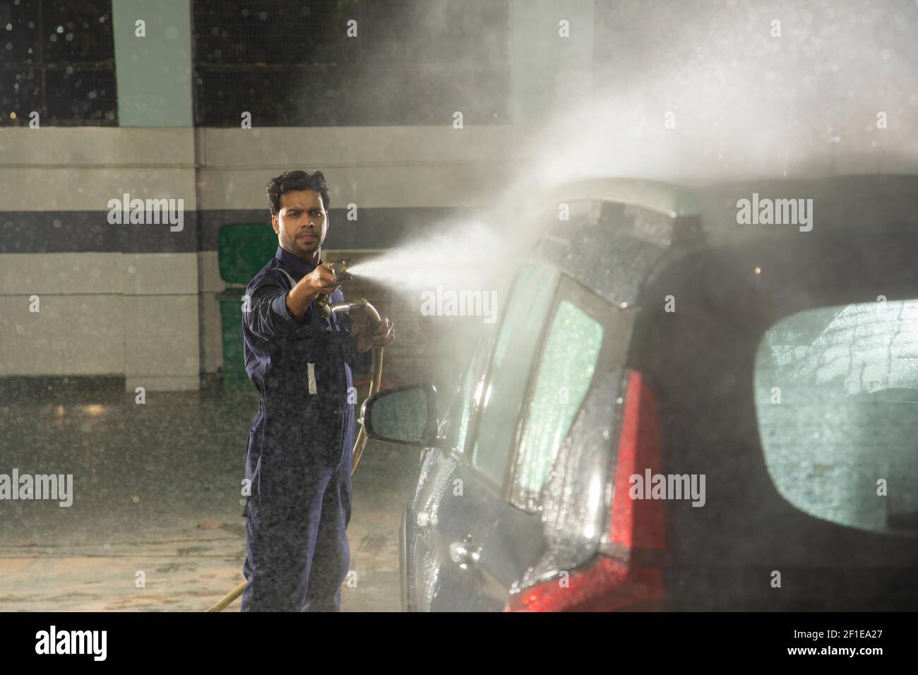 Technician  cleaning the car with a high pressure washer at a car wash Stock Photo
