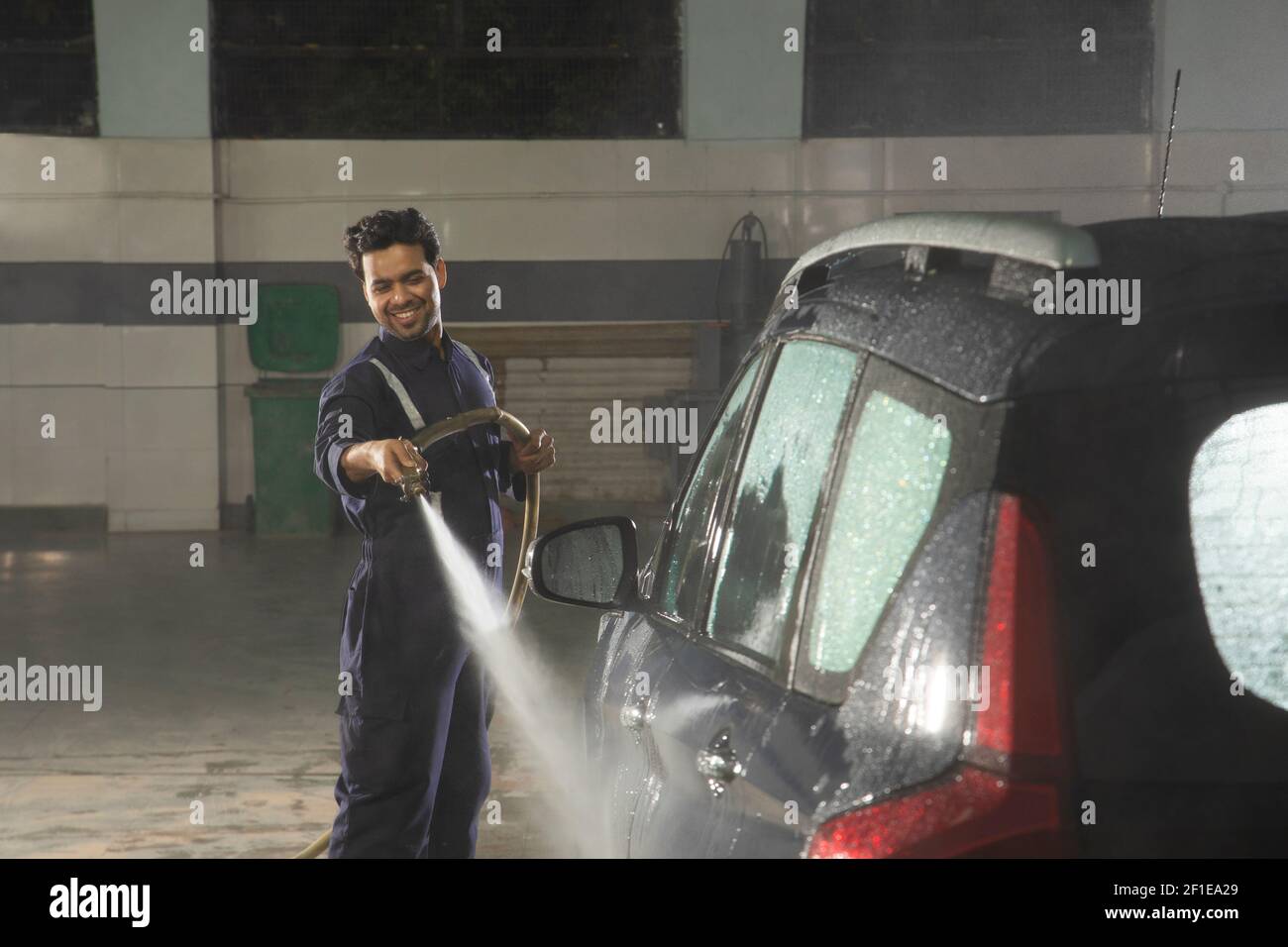 Technician cleaning the car with a high pressure washer at a car wash ...