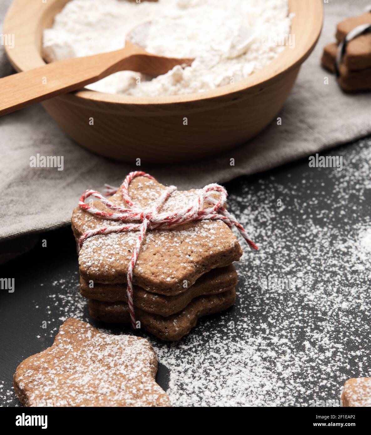 baked star-shaped gingerbread cookie sprinkled with powdered sugar on a black table and ingredients, close up Stock Photo