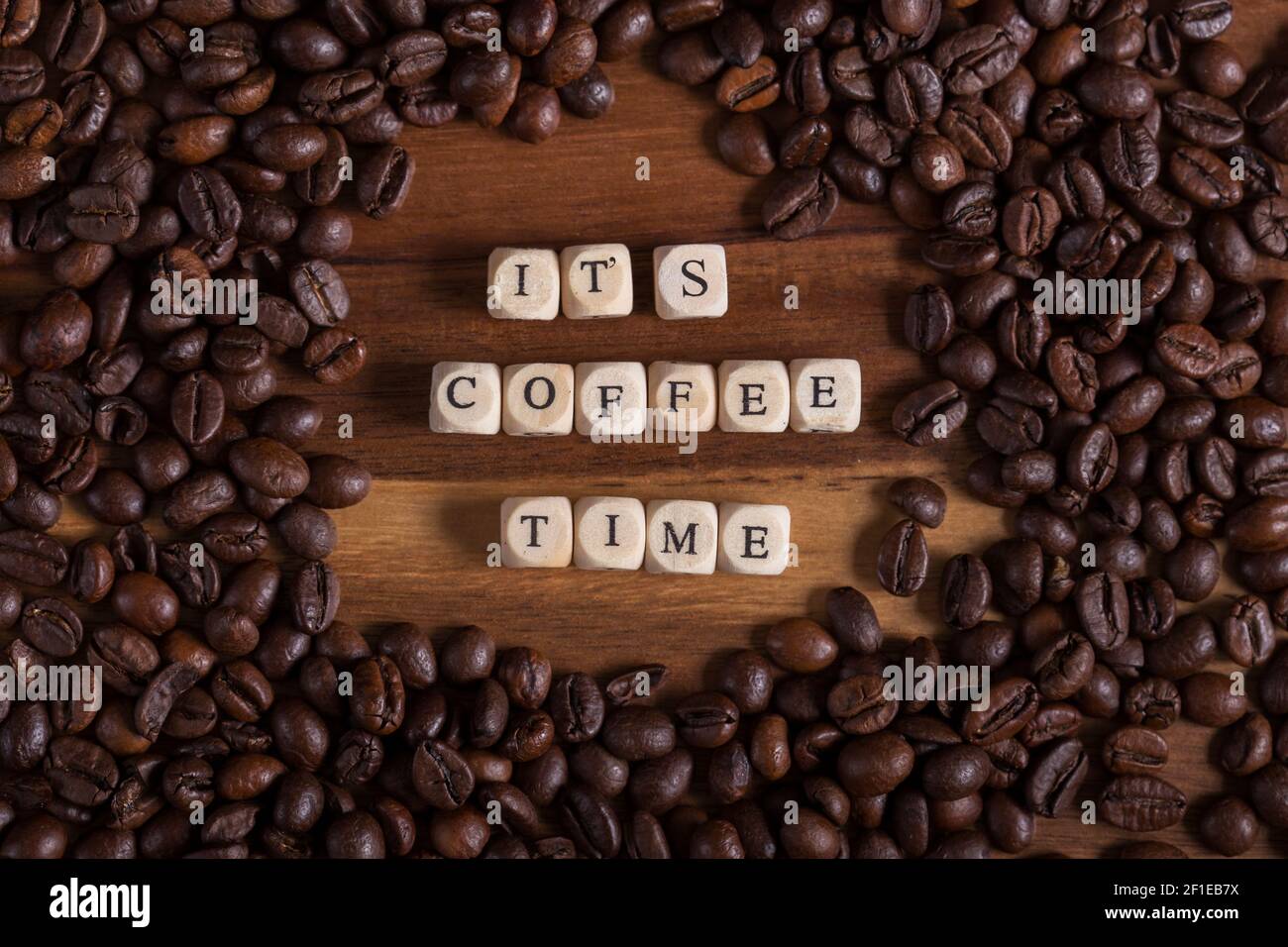 Beans Coffee all around on a wooden table. it's coffee time with a wooden cube letters. aroma of fresh coffee. Stock Photo