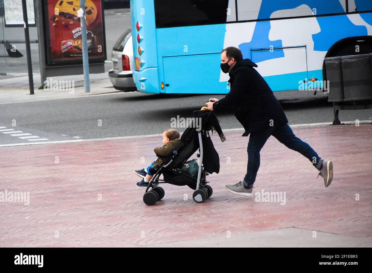 Stressed father pushing a stroller with his son inside. He is running because he is late. Family, lifestyle, people, moment, everyday, real life. Stock Photo