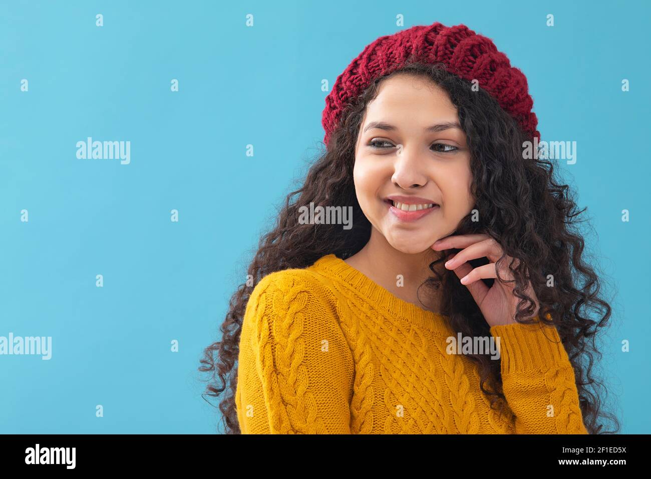 PORTRAIT OF A TEENAGE GIRL IN WOOLEN CLOTHES LOOKING AWAY AND POSING Stock Photo