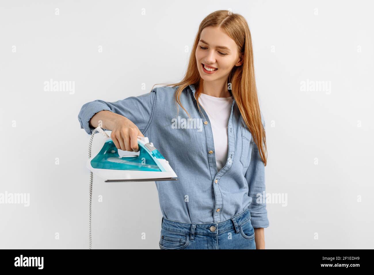 Young woman holding an iron, ironing clothes, daily life, housework, on