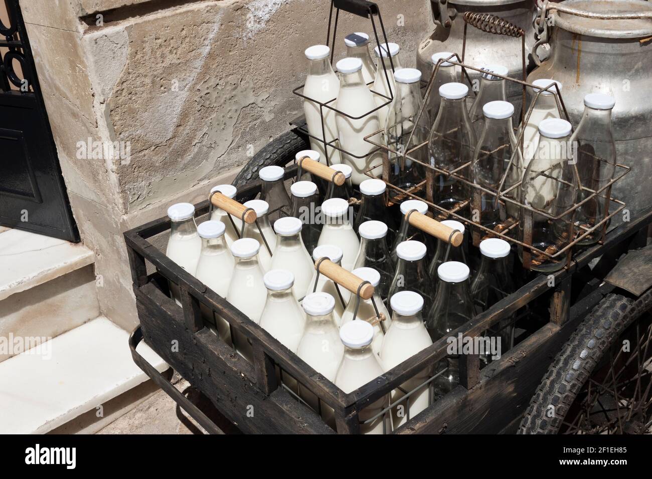 Bottles and aluminum cans of milk for delivery in vintage rusty milkman bicycle. Stock Photo