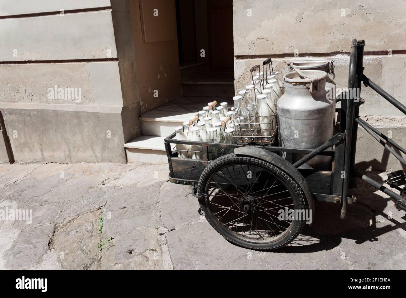 Bottles and aluminum cans of milk for delivery in vintage rusty milkman bicycle. Stock Photo