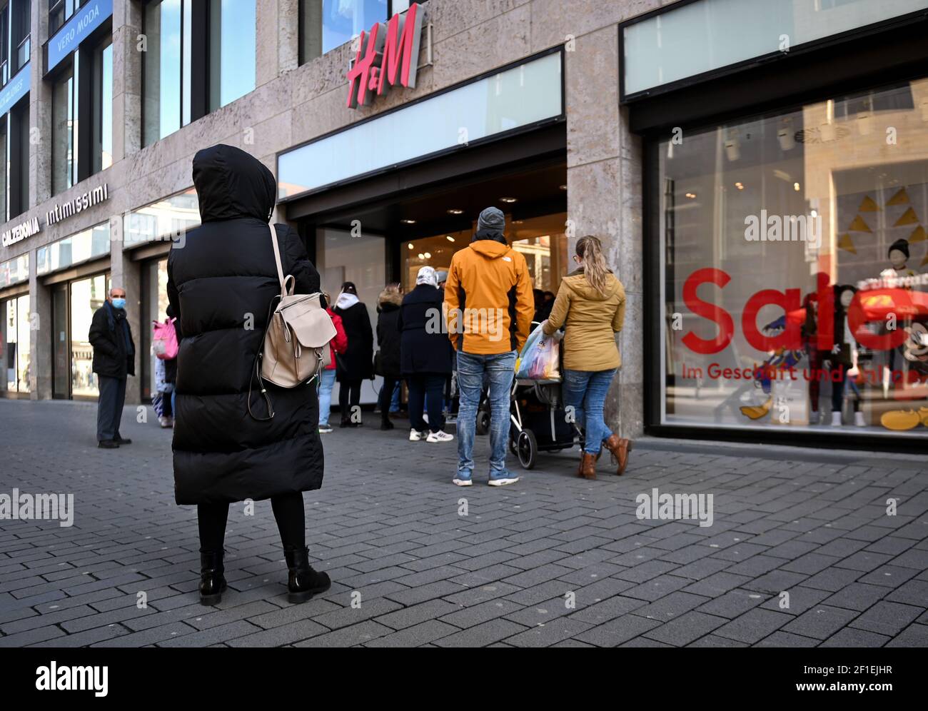 Leipzig, Germany. 08th Mar, 2021. Customers queue outside the entrance of  an H&M store in Petersstraße. After a week-long corona-induced lockdown,  many retailers are offering a new concept with "Click & Meet",