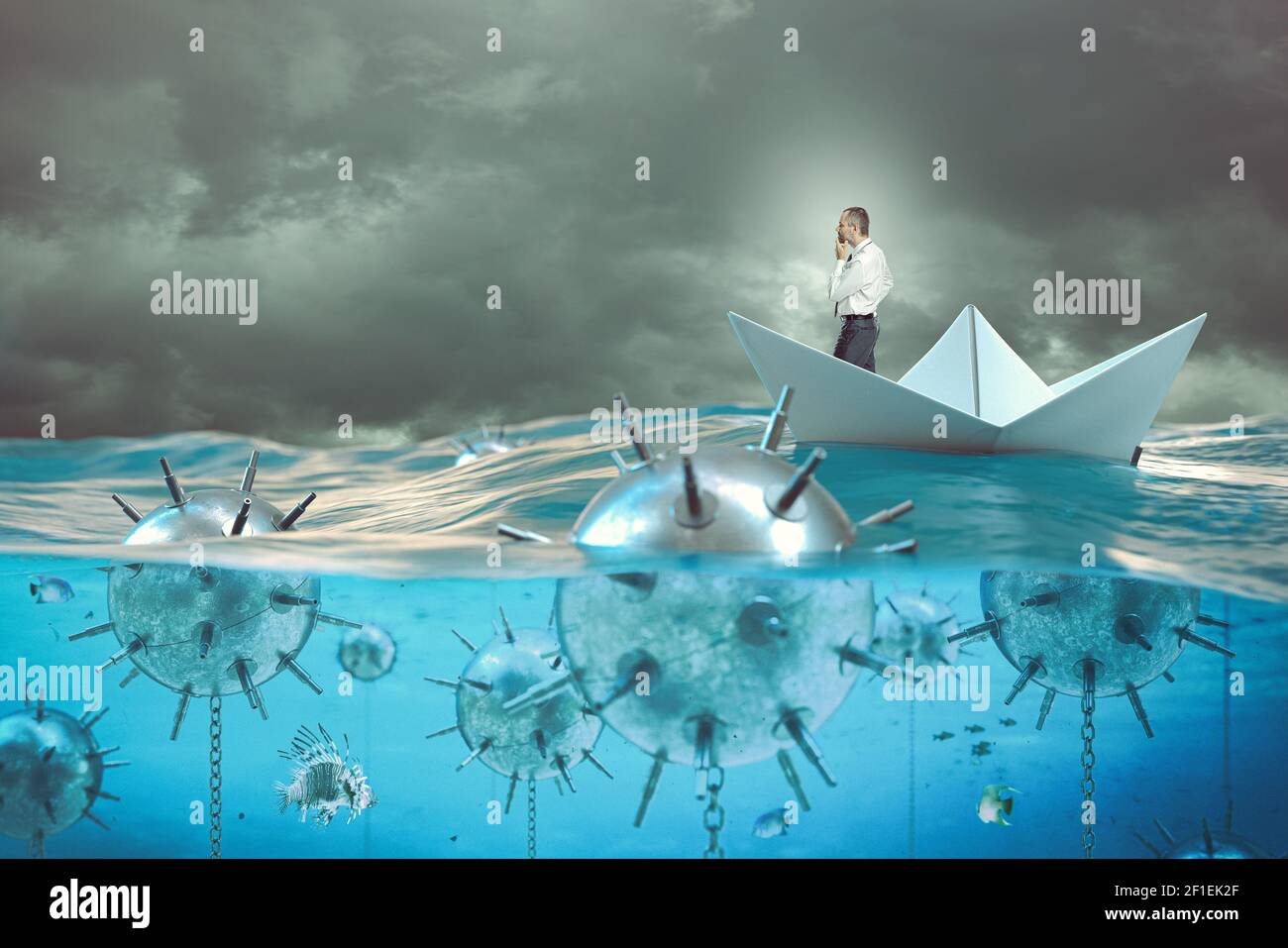pensive businessman on a paper boat in the sea surrounded by mines. Stock Photo