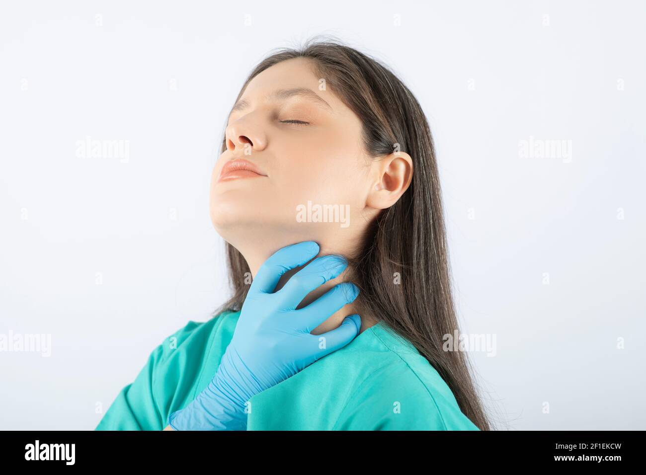 Photo of a young woman doctor in green uniform touching her neck Stock ...