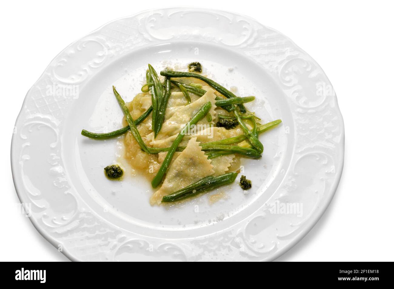 ravioli topped with butter sauce, parmesan and green beans in white plate isolated on white in top view Stock Photo